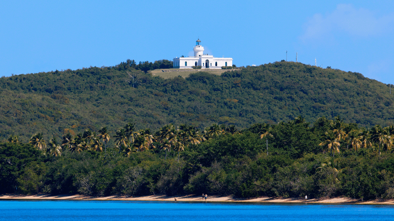 El Faro de Fajardo en la cima de una colina verde con vegetación tropical y costa al frente bajo cielo azul, en la reserva natural Cabezas de San Juan en Las Croabas, Fajardo. (Foto: Getty Images)